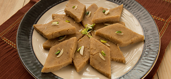 Flour halwa pieces garnished with nuts on plate