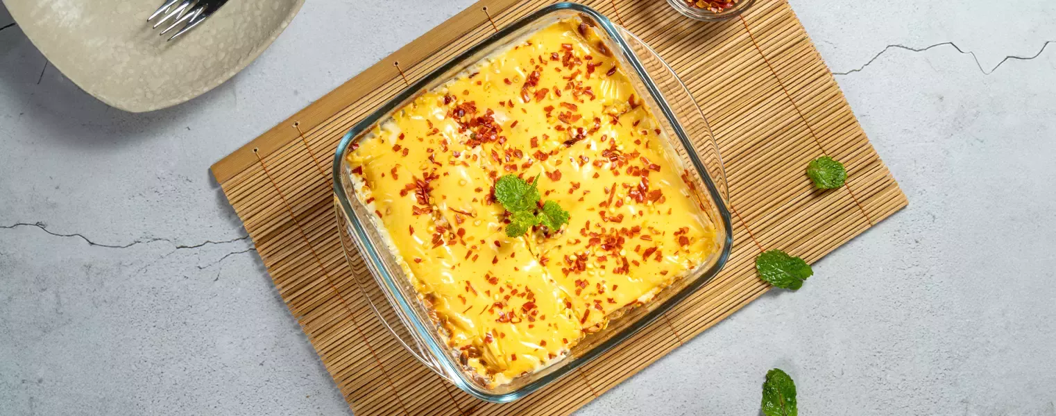 Baked maggi noodles with melted cheese and chili flakes in glass dish